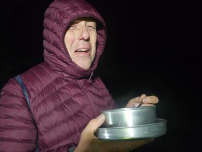 Dave looks into the camera with a pan of steaming soup and noodles. It's pitch black in the early hours of the morning.